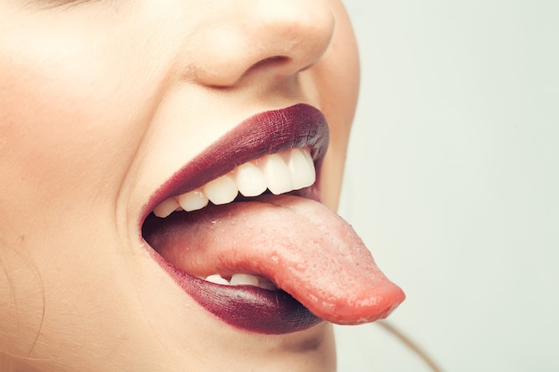 Weiblicher offener lächelnder Mund mit lila Lippenstift und Zunge der sexy Lippen