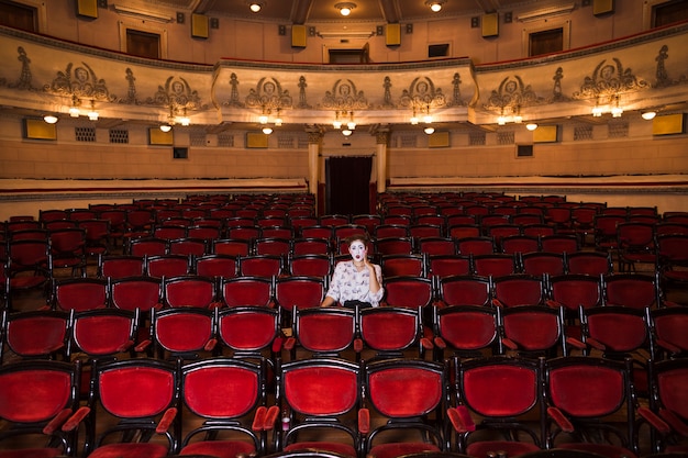 Weiblicher Pantomimekünstler, der alleine in einem Auditorium sitzt