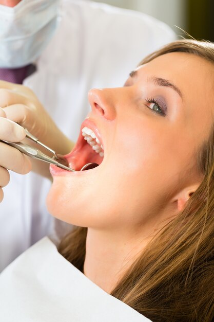 Weiblicher Patient mit dentista zahnmedizinischer Behandlung, tragenden Masken und Handschuhen