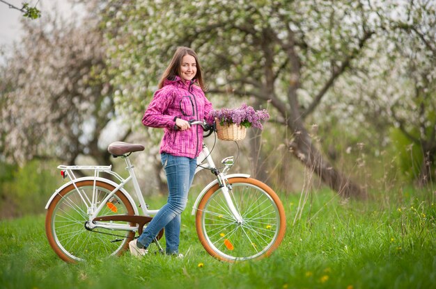 Weiblicher Radfahrer mit weißem Garten des Fahrrades der Weinlese im Frühjahr