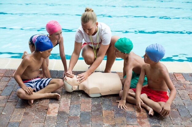 Foto weiblicher rettungsschwimmer, der kindern am pool rettungstraining gibt