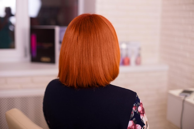 Weiblicher Rücken mit kurzen, glatten, roten Haaren im Friseursalon