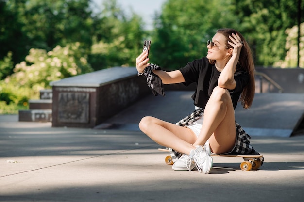 Weiblicher Skater mit einem Skateboard, das in der Eisbahn sich entspannt