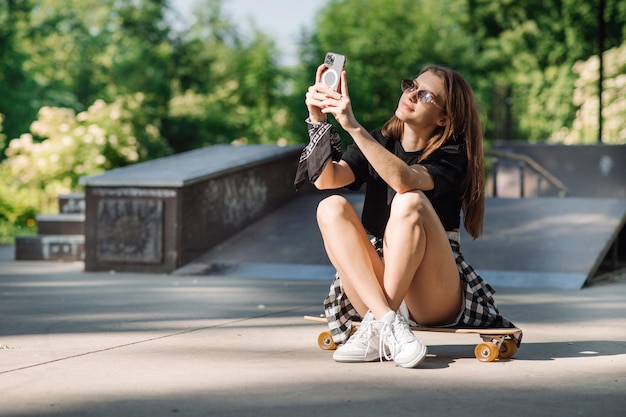 Weiblicher Skater mit einem Skateboard, das in der Eisbahn sich entspannt