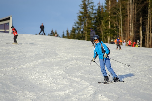 Weiblicher Skifahrer, der abwärts am Skiort Ski fährt