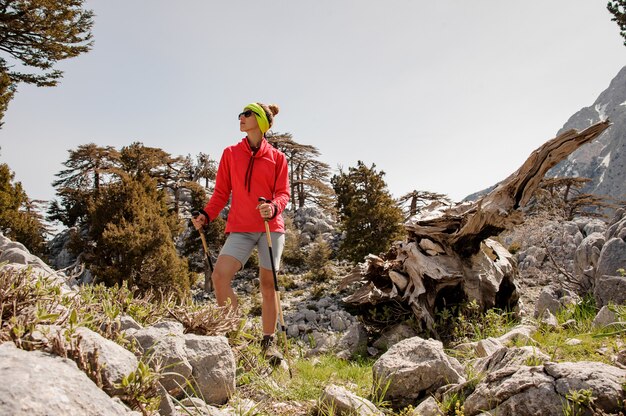 Weiblicher Tourist mit dem Wandern der Ausrüstung unter Felsen