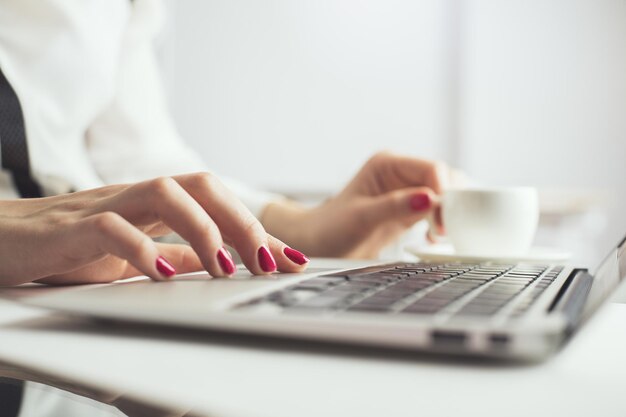 Weiblicher trinkender Kaffee unter Verwendung des Laptops