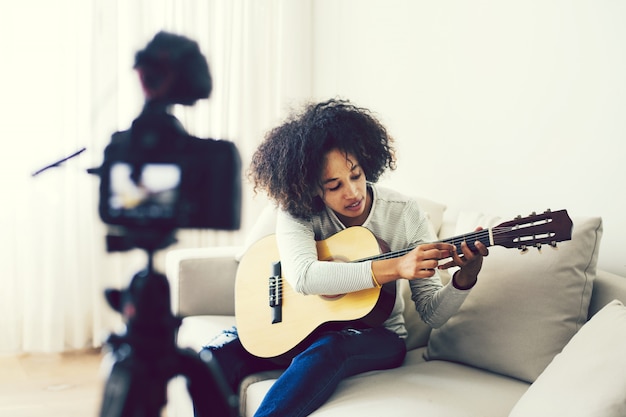 Weiblicher Vlogger, der eine Gitarre spielen filmt