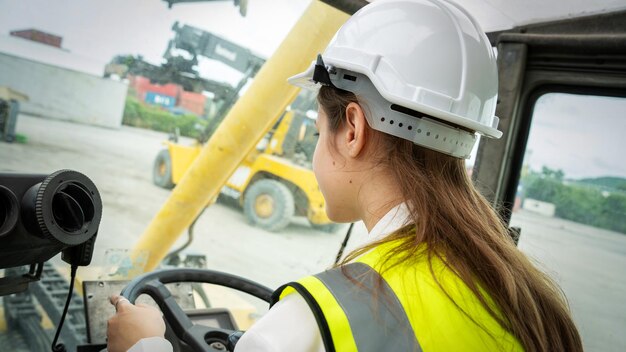 Weiblicher Vorarbeiter Fahren Sie einen Gabelstapler-Container-Frachtgabelstapler und verwenden Sie Walkie-Talkie für die Kommunikation während Fahrsteuerungs-Gabelstapler-Konzeptdienst und Transportlogistik