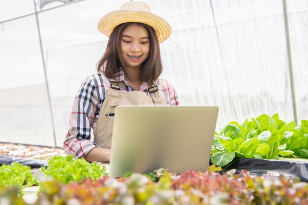 Weiblicher Wasserkulturlandwirt, der Gemüsewachstumsinformationen sammelt und Laptop verwendet