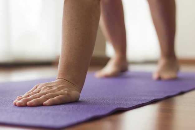 Weiblicher Yogi-Anfänger übt Adho Mukha Svanasana-Pose Nahaufnahme auf der Hand der Frau auf Yogamatte