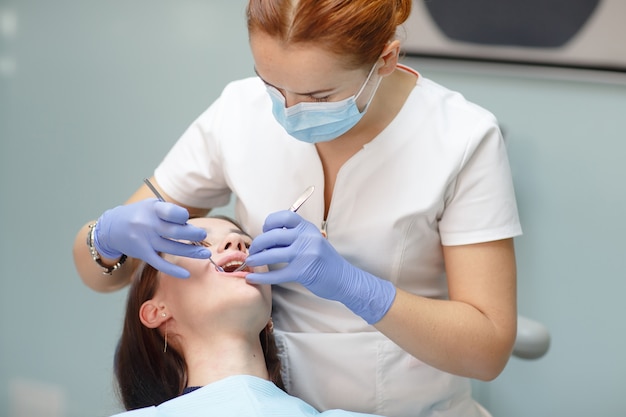 Weiblicher Zahnarzt, der geduldige Frauenzähne überprüft