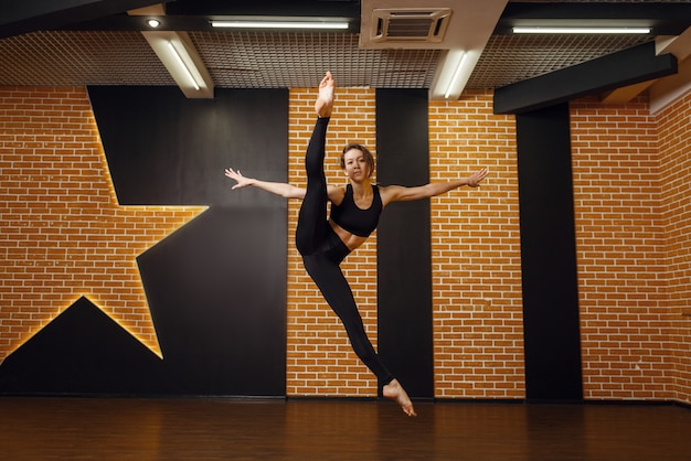 Weiblicher zeitgenössischer Tanz, Sprung in Bewegung, Training im Studio. Tänzerin beim Training im Unterricht, modernes Ballett, Eleganztanz, Dehnübungen