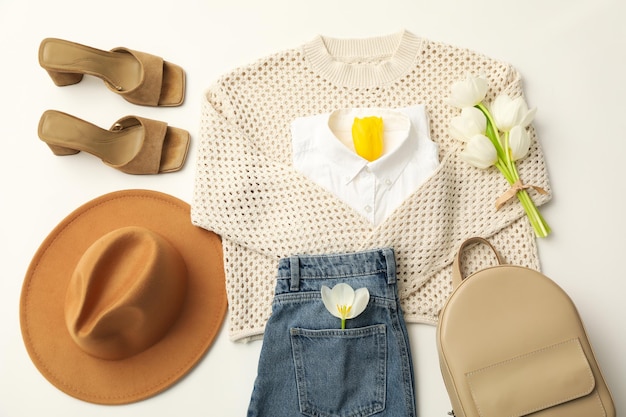 Weibliches Frühlings-Outfit mit Accessoires und Blumen auf weißem Hintergrund