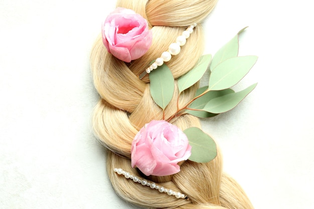 Weibliches Haar mit Blumen und Haarspangen auf hellem Hintergrund