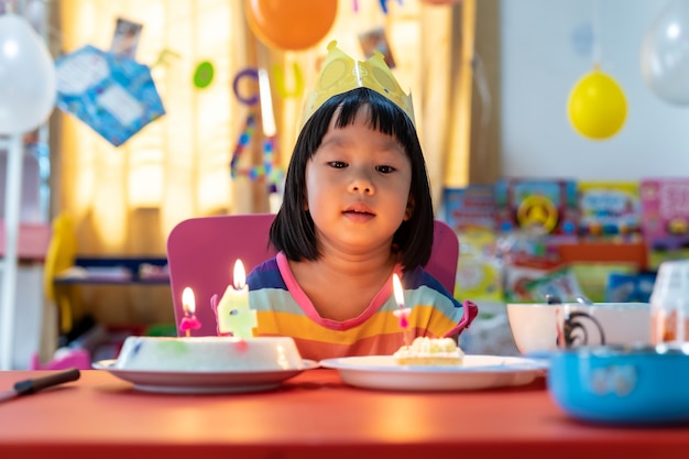 Weibliches Kind mit Geburtstagstorte und Kerze