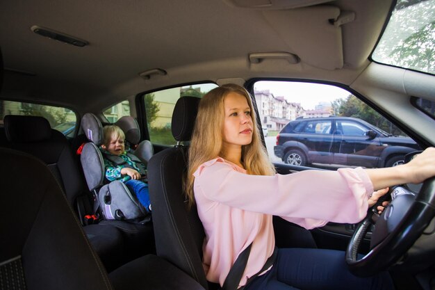 Weibliches Kindermädchen fährt das Auto und liefert Baby Boy sitzt auf dem Autositz