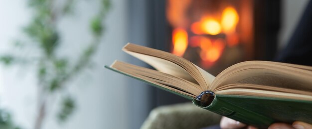 Weibliches Lesen eines Buches durch den Kamin Gemütlicher Winterlebensstil