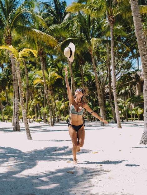 Weibliches Modell, das in einem Bikini auf einem paradiesischen Strand mit Palmen aufwirft