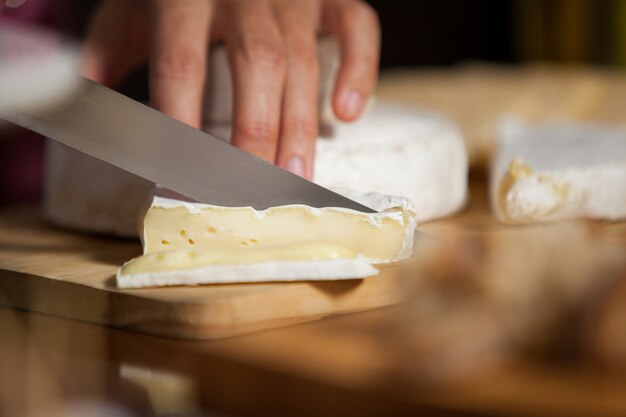 Foto weibliches personal, das käse am schalter im markt schneidet