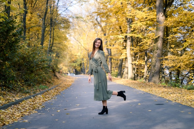 Weibliches Porträt. Brunettefrauenporträt im Herbstpark, der olivgrünes Kleid trägt