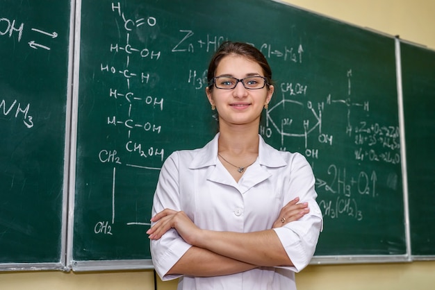 Weibliches Porträt. Chemielehrer, der in der Nähe der Klassentafel steht und darauf zeigt