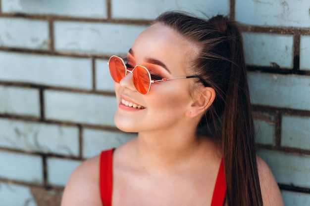 Weibliches Porträt in der roten Sonnenbrille im Freien