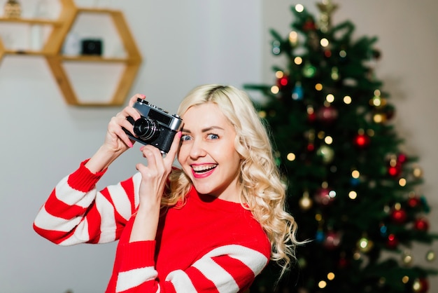 Weibliches Porträt mit schönem Lächeln und Locken auf blonden Haaren. Frau hält Kamera-Dame-Fotograf.