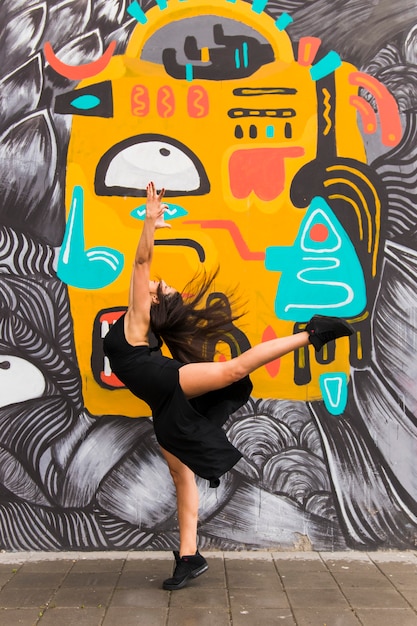 Foto weibliches tänzertanzen des hip-hops gegen graffitiwand