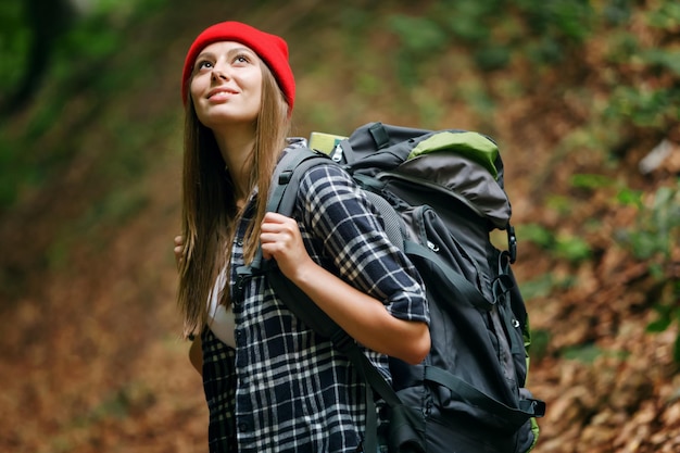 Weibliches Wandermädchen mit Rucksack, das beim Trekking draußen wegschaut