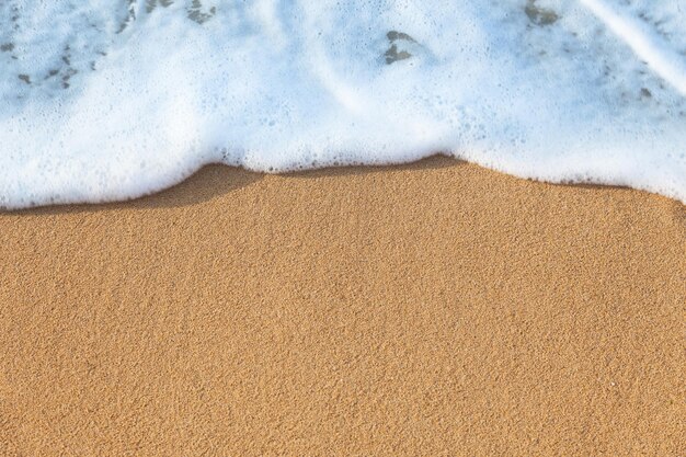 Weiche Welle des Meeres auf dem Hintergrund des sandigen Strandes