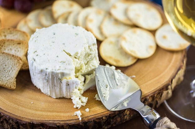 Weicher aromatisierter Rahmkäse mit Knoblauch und feinen Kräutern auf einem Holzbrett mit Crackern.