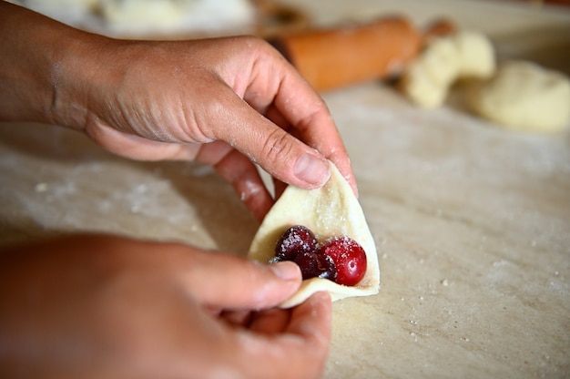 Weicher Fokus auf Konditorhand, die Kirschknödel formt. Schritt für Schritt zum Kochen von Knödeln. Nahaufnahme, Essen Hintergrund