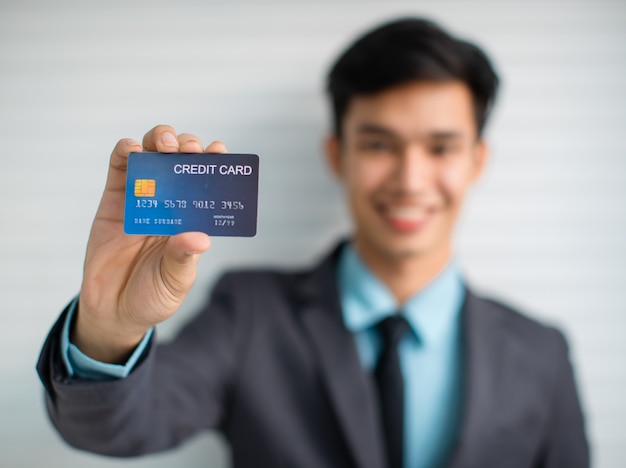 Weicher Fokus des männlichen Unternehmers, der Kreditkarte vorführt, während er für Bankdienstleistungen wirbt