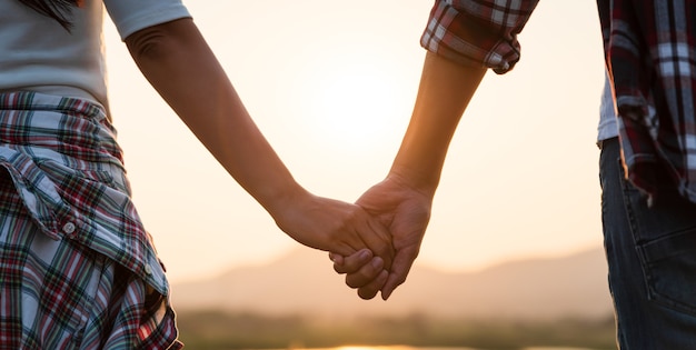 Weicher Fokus von zwei Partnern, die bei Sonnenuntergang die Hand vor dem Berg halten