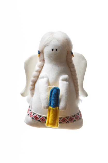 Weicher Spielzeugengel aus weißem Stoff mit Flügeln, der eine Kerze in der Farbe der ukrainischen Flagge blau und gelb hält