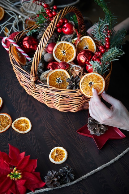 Weidenkorb mit gestreiften Zuckerstangen, getrockneten Orangenscheiben, Zapfen und Geschenken.
