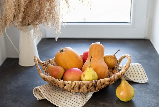 Weidenkorb mit Kürbisäpfeln Birnen auf dunkler Küchentheke Herbstsaisonzusammensetzung