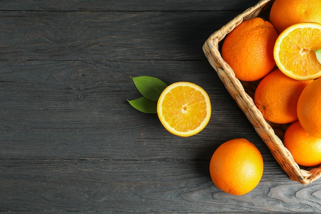 Weidenkorb mit reifen Orangen auf Holztisch.