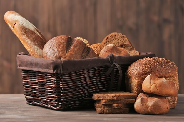 Weidenkorb mit verschiedenen frischen Brotsorten auf Holztisch