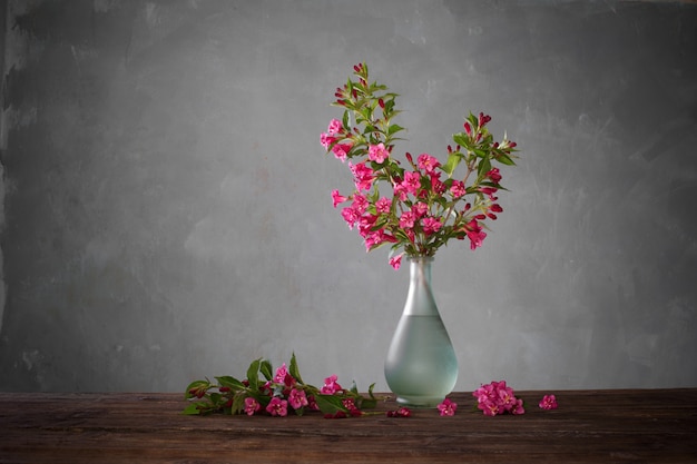 Weigela Blumen in Glasvase auf Holztisch