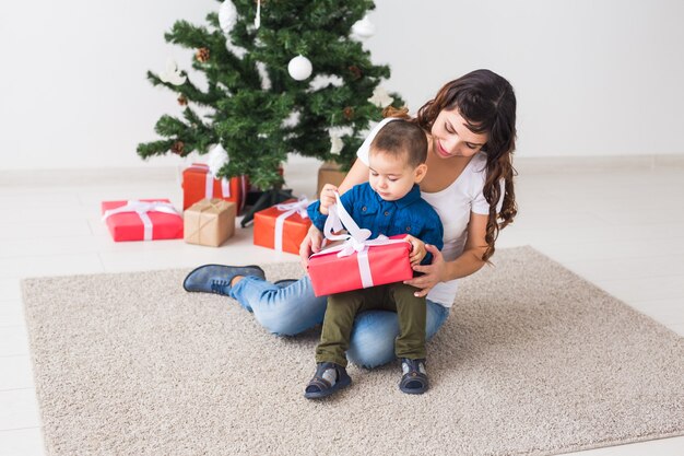 Weihnachten, Alleinerziehende und Feiertagskonzept - Netter kleiner Junge, der Weihnachtsgeschenk für seine Mutter zu Hause hält.