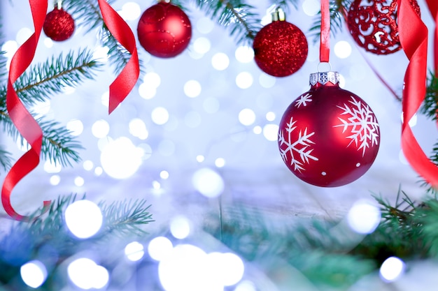 Weihnachten-Bokeh-Hintergrund mit Tannenzweigen, Bändern und roter aufwändiger Kugel.