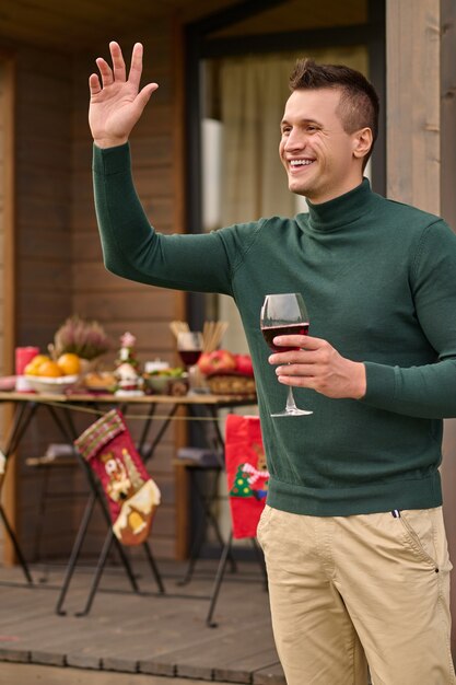 Weihnachten feiern. Ein junger Mann mit einem Glas Wein in der Hand