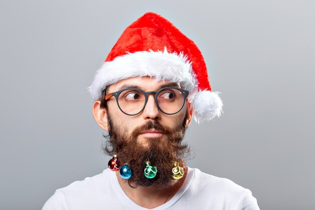 Weihnachten, Feiertage, Friseursalon und Stilkonzept - junger hübscher bärtiger Weihnachtsmannmann mit vielen