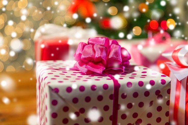 weihnachten, feiertage, geschenke, neujahr und feierkonzept - nahaufnahme von geschenkboxen über weihnachtsbaumlichtern