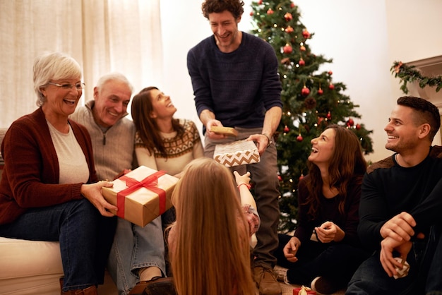 Weihnachten glücklich und Geschenk mit der Familie im Wohnzimmer für Feiertage und festliche Dankbarkeit Entspannen Sie sich, lächeln Sie und schenken Sie den Eltern, die den Kindern zu Hause eine Schachtel für Inhalte auf der Weihnachtsfeier geben