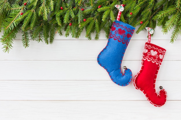 Weihnachten Hintergrund. Weihnachtstannenbaum mit den Dekoration-, Roten und Blauenweihnachtssocken auf weißem Hintergrund des hölzernen Brettes mit Kopienraum
