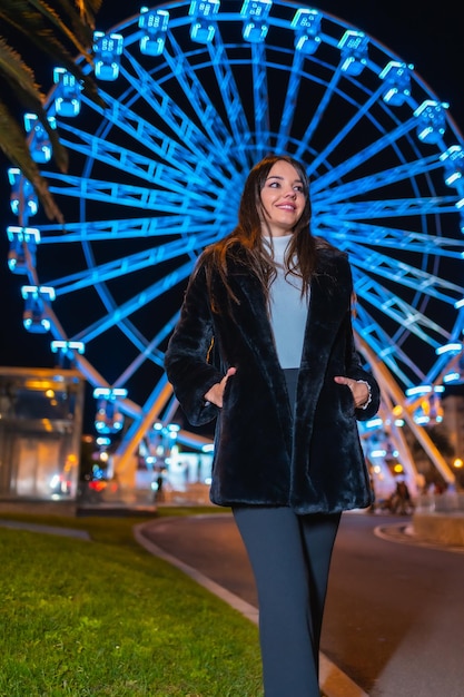 Weihnachten in der Stadt Winterdekoration Junger Mann genießt die Nacht auf einem beleuchteten Riesenrad