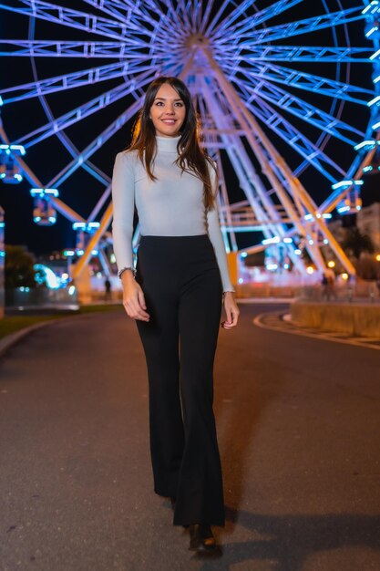 Weihnachten in der Stadt Winterdekoration Porträt einer jungen Frau, die die Nacht auf einem beleuchteten Riesenrad genießt